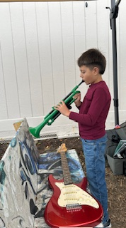Boy plays trumpet near electric guitar